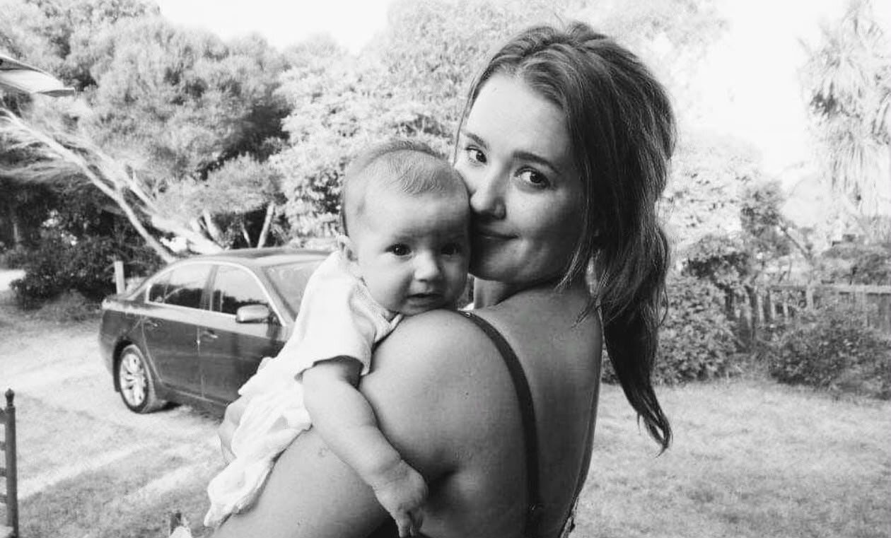 Maddy Smith in black and white, holding her baby daughter close