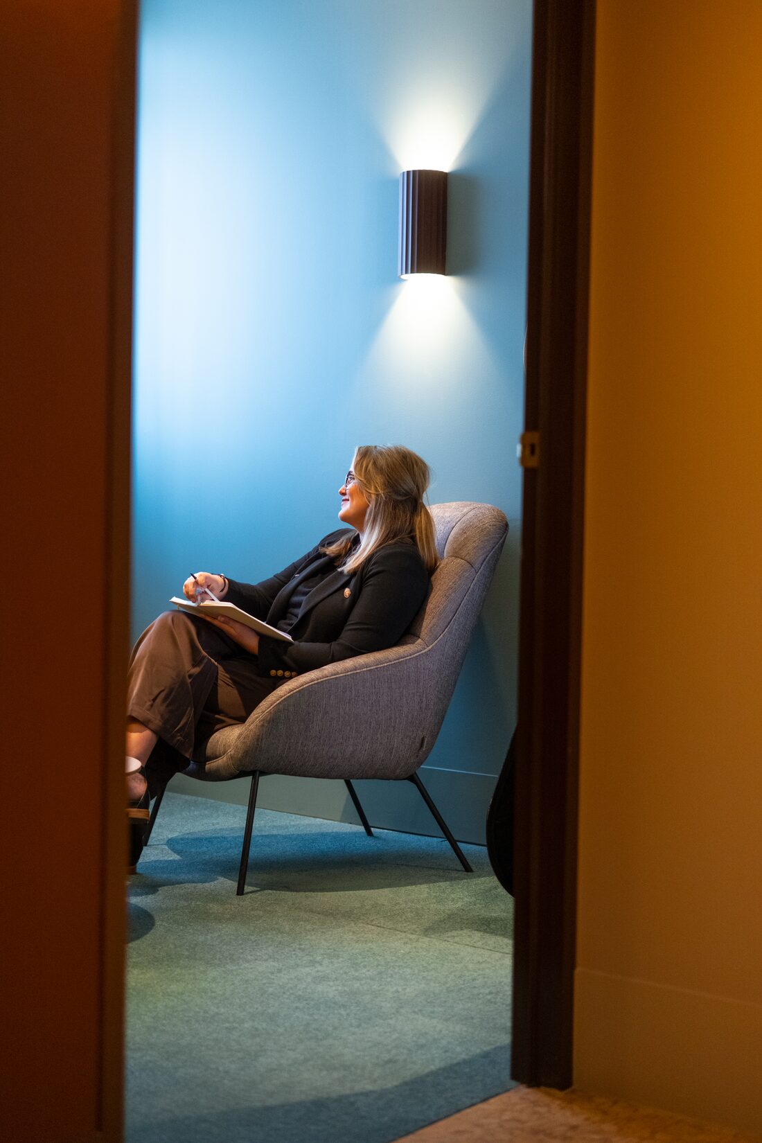Maddy Smith sitting quietly in a lamplit room, looking towards the window